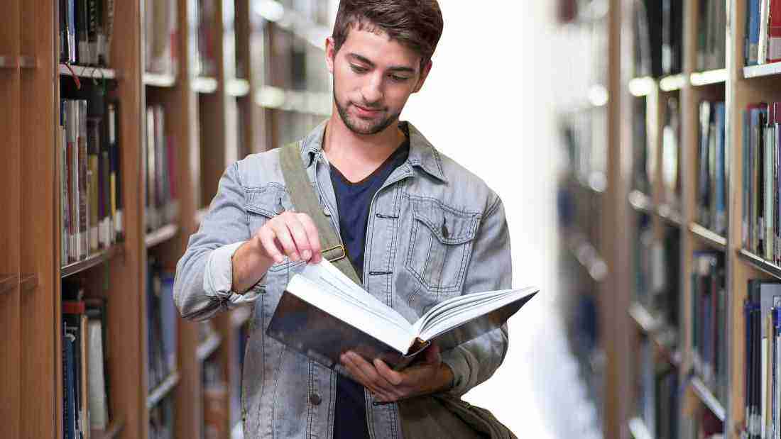 A young man reading a book in the library