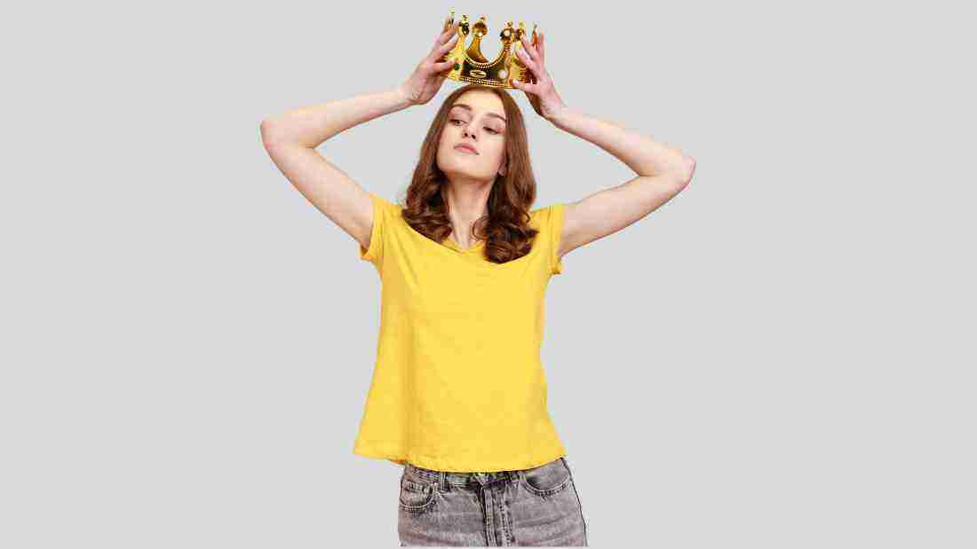 A woman putting on a golden crown