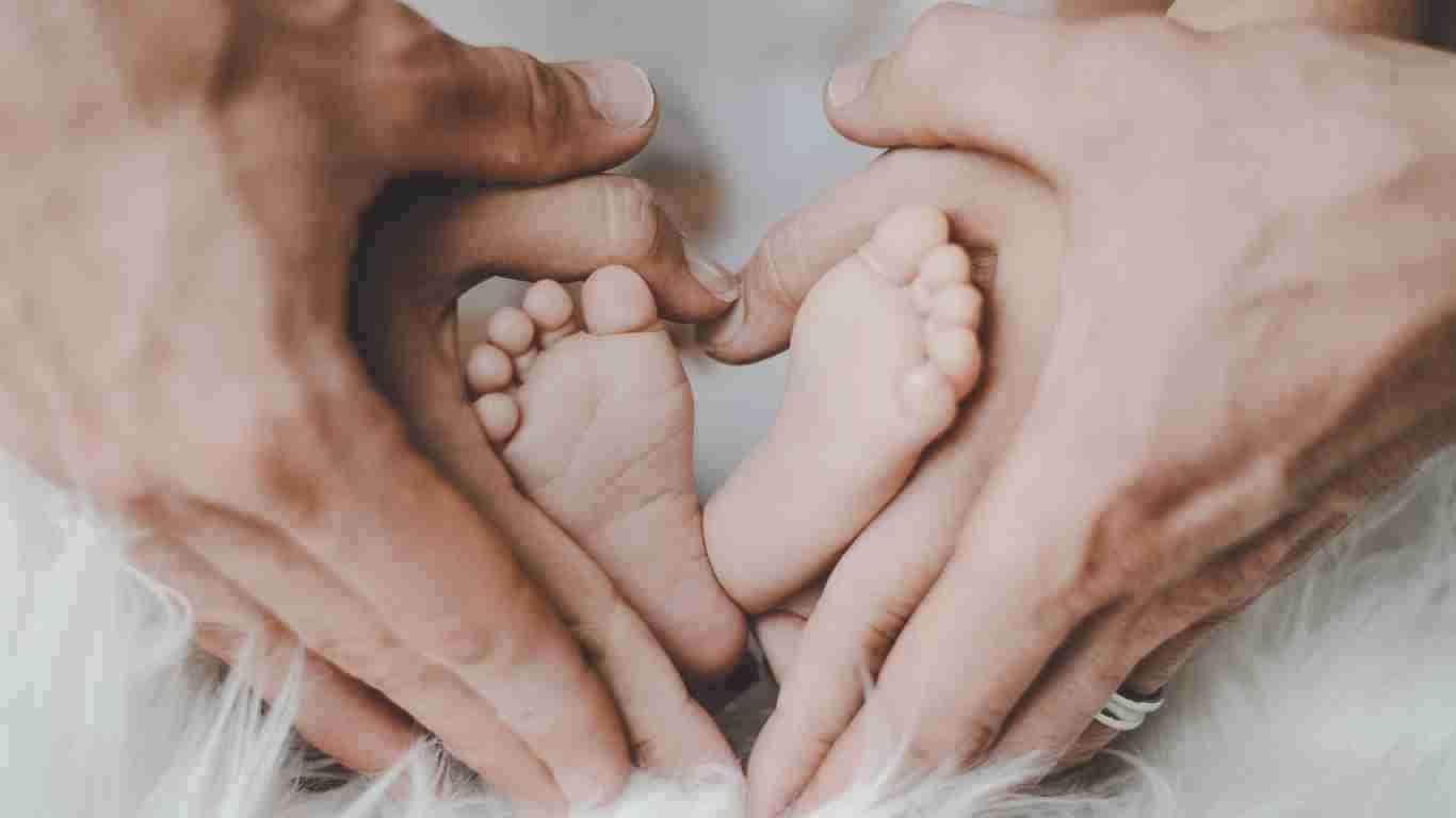 A photo showing parents' hands around their baby's feet