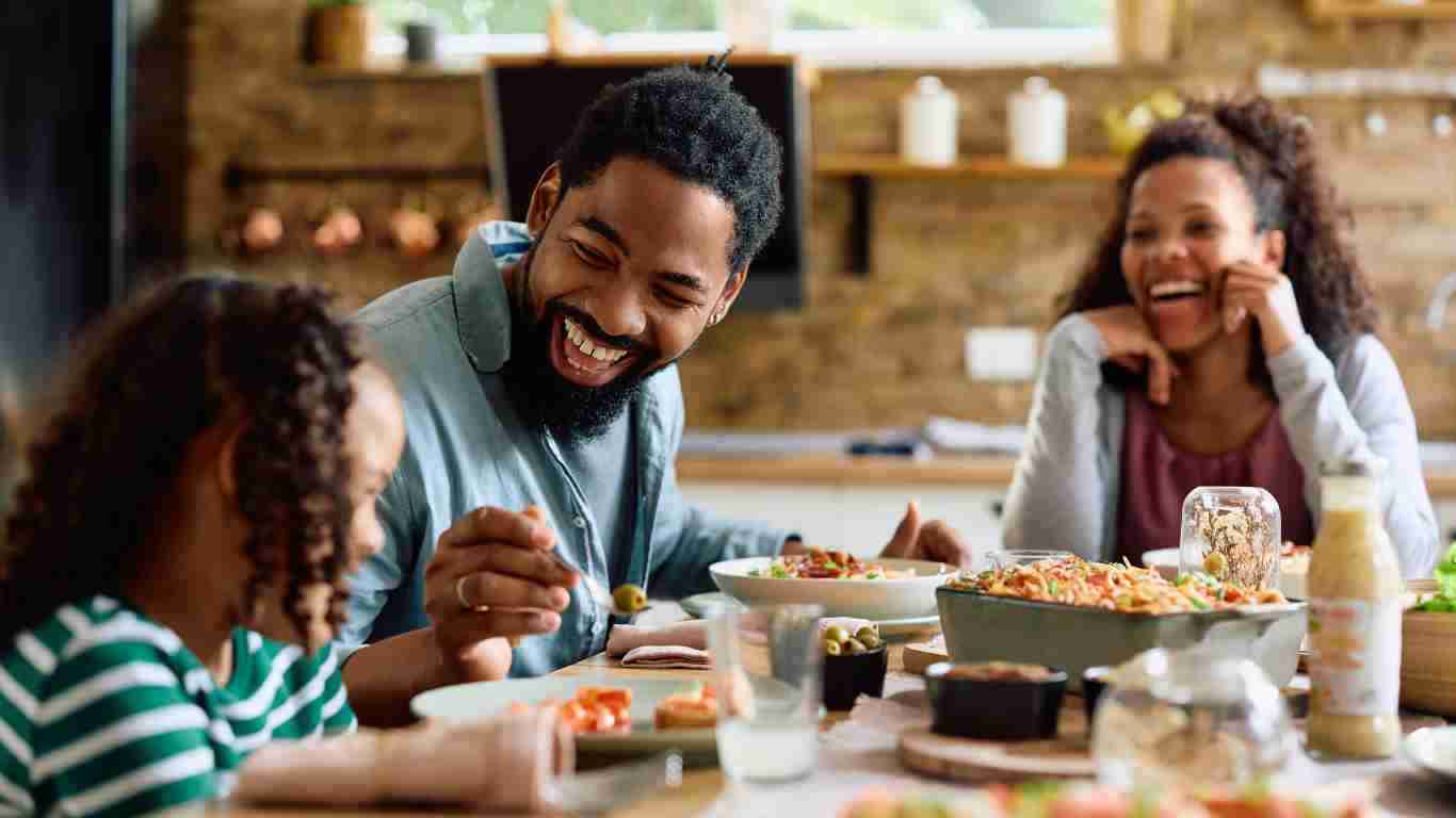Parents and their daughter laughing together as they eat lunch