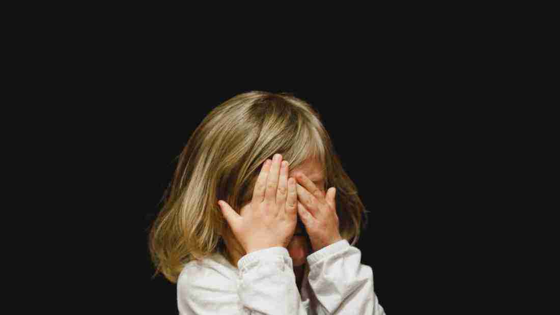 A little girl covering her face