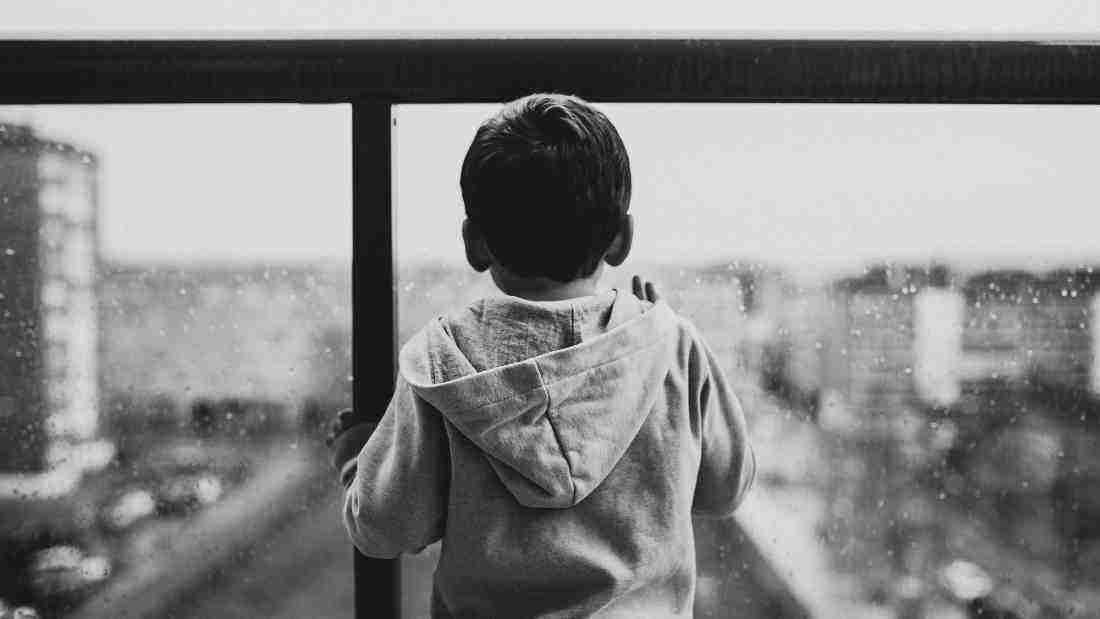 A young boy looking out at the rain