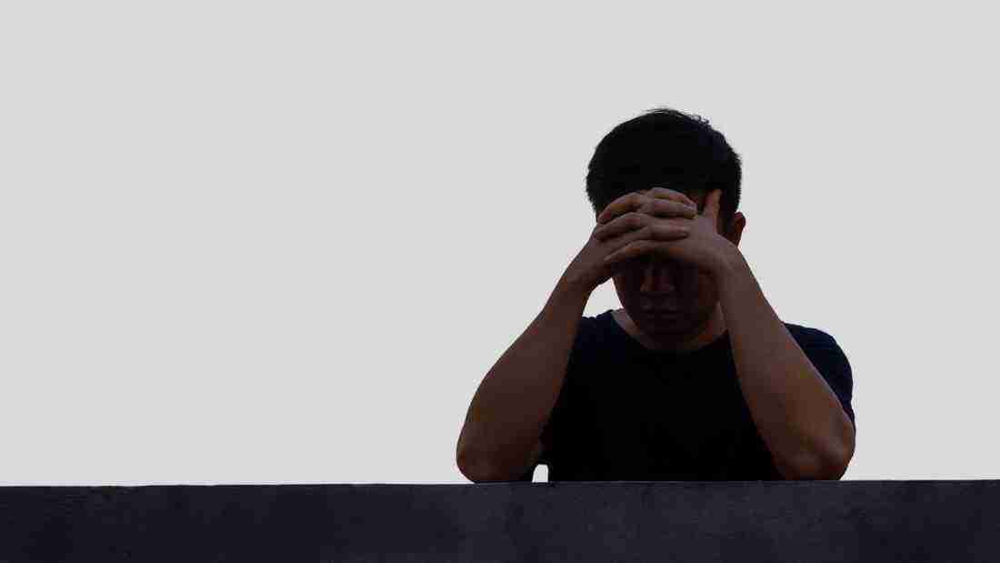 A very upset man leaning on a wall