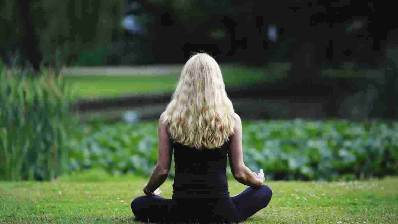 A woman meditating on a lovely green lawn
