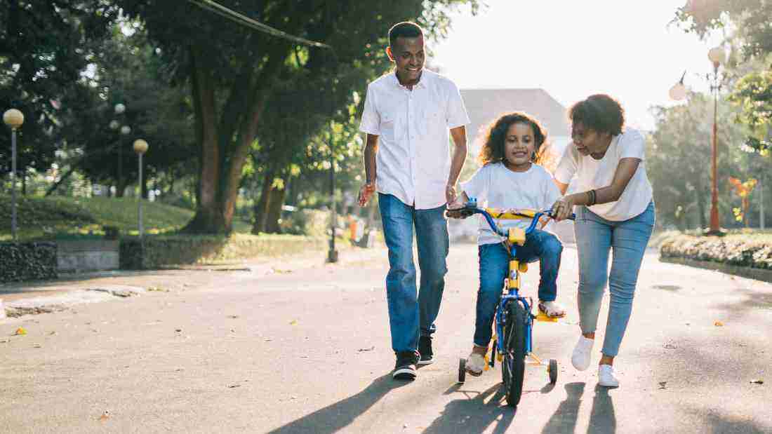 Parents teaching their daughter how to ride a bike