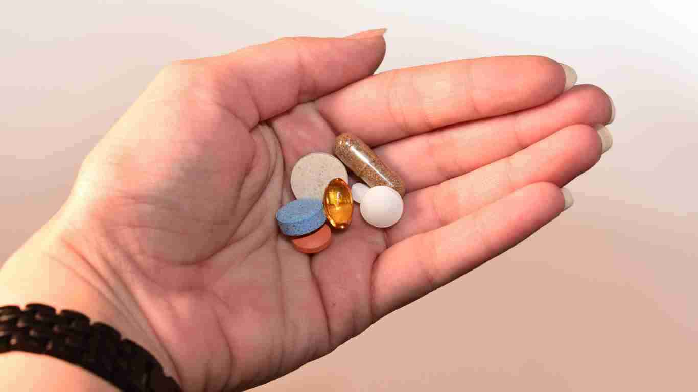 A hand holding several pills