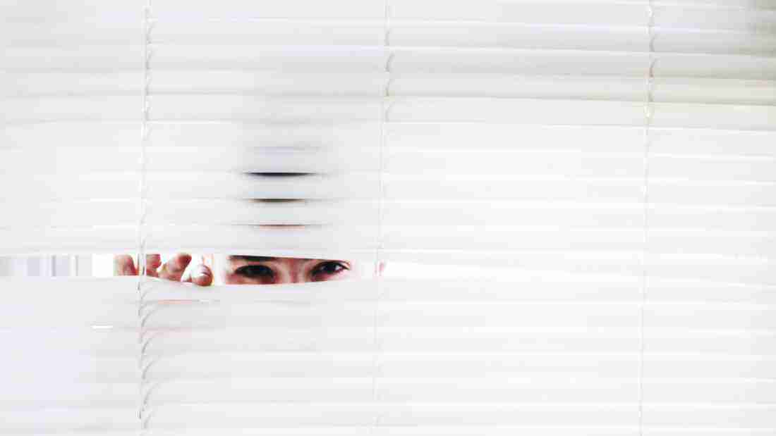 A woman peeping through blinds
