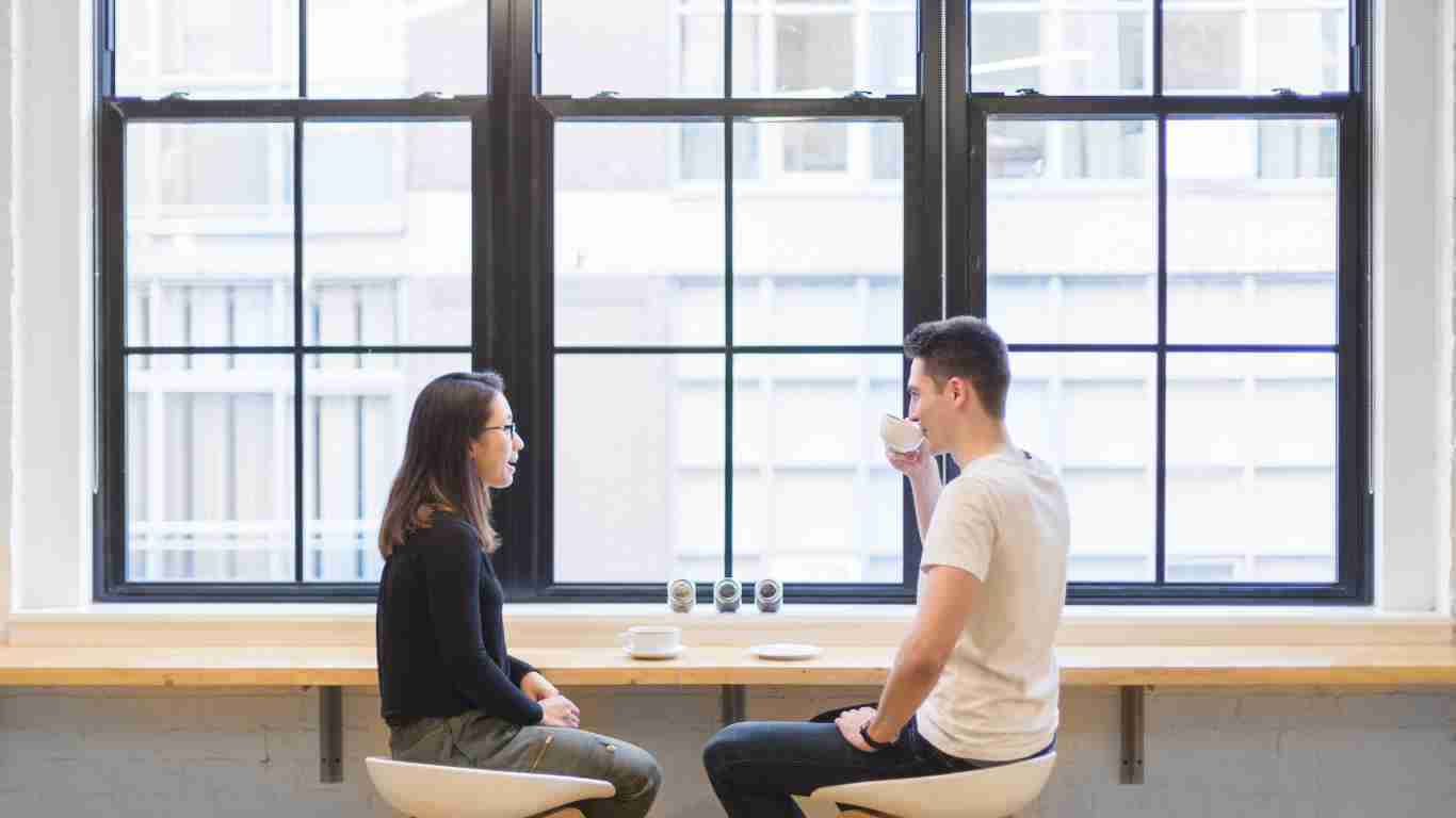 A couple talking in front of a massive window