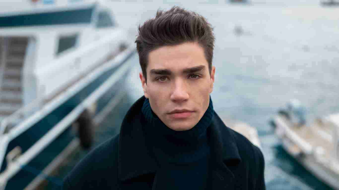 A male model posing in front of a yacht