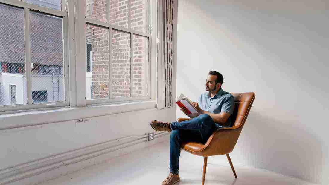 A man reading a book in a comfortable armchair