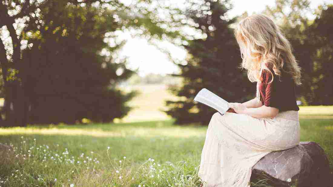 A woman reading a book in a meadow