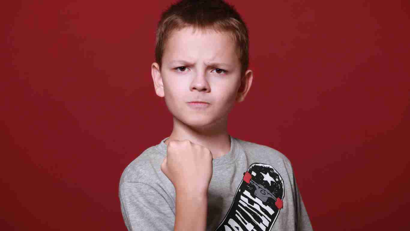 An angry little boy clenching his fist
