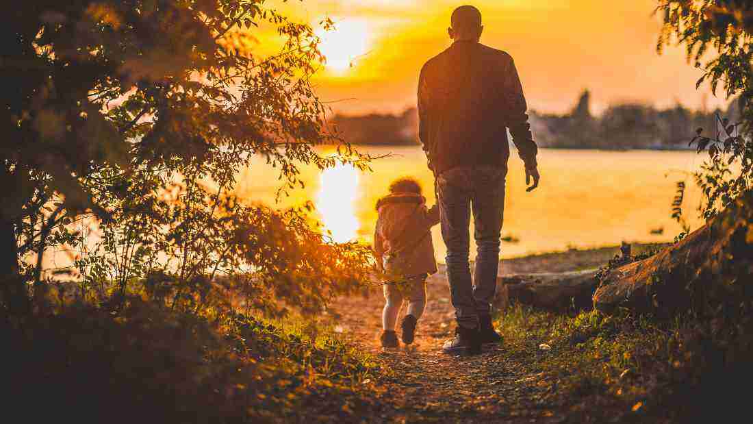 A father holding his child's hand on a walk
