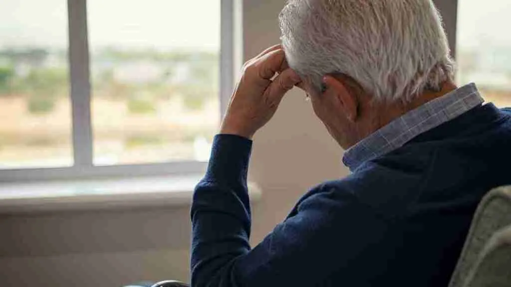 A sad old man sitting alone in his living room.