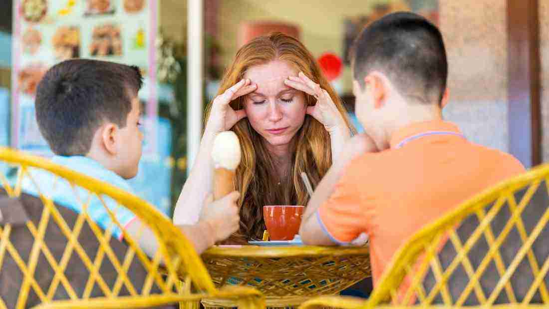 A stressed woman sitting at a table with her two sons