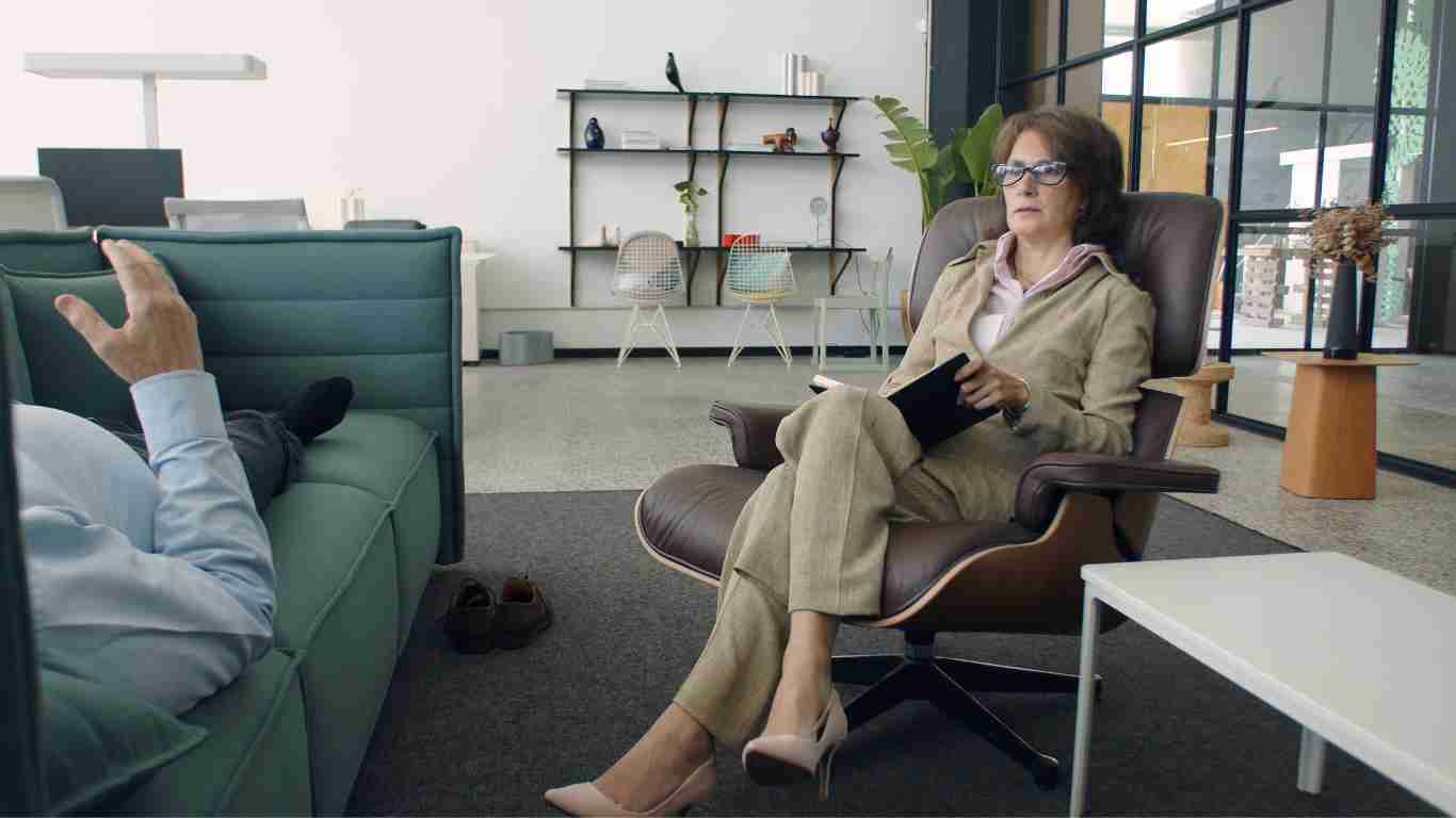 A therapist talking to her client, who is lying on a couch