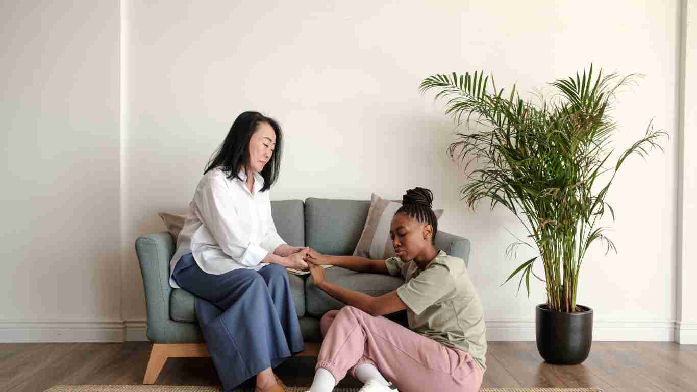 A therapist comforting her client by holding her hand as they speak