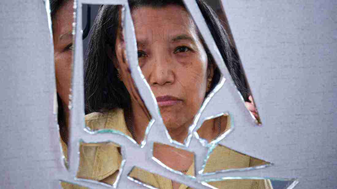 A woman's reflection in a shattered mirror