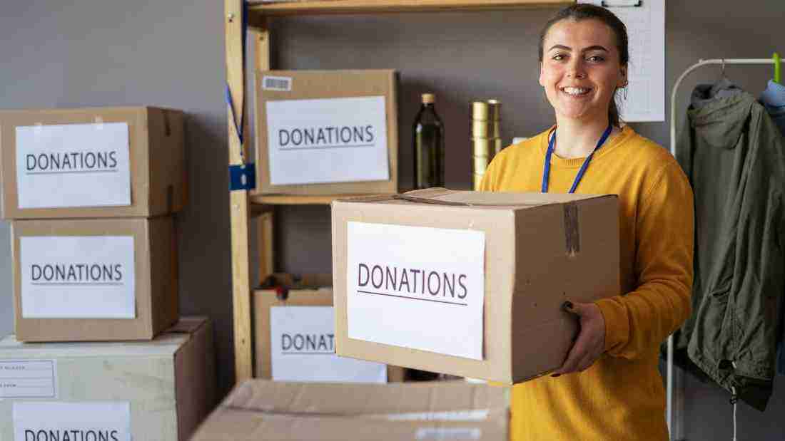 A woman carrying boxes of donated items
