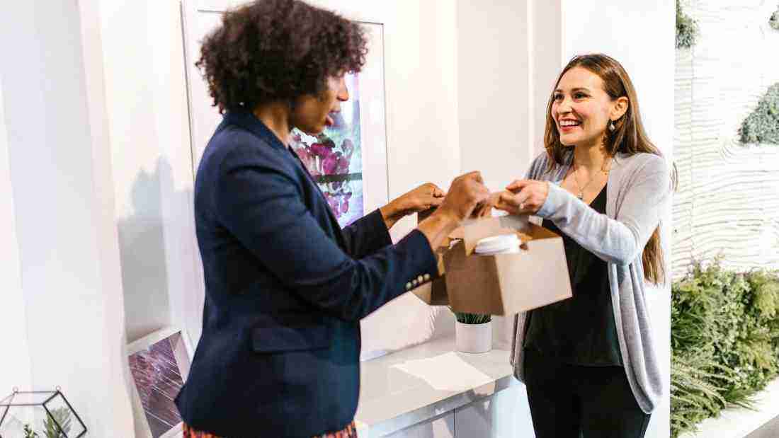 A woman giving another woman some generous gifts
