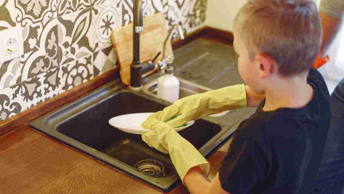 A little boy washing the dishes