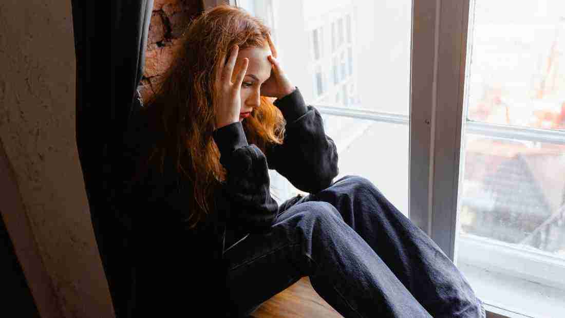 A young woman sitting on a windowsill