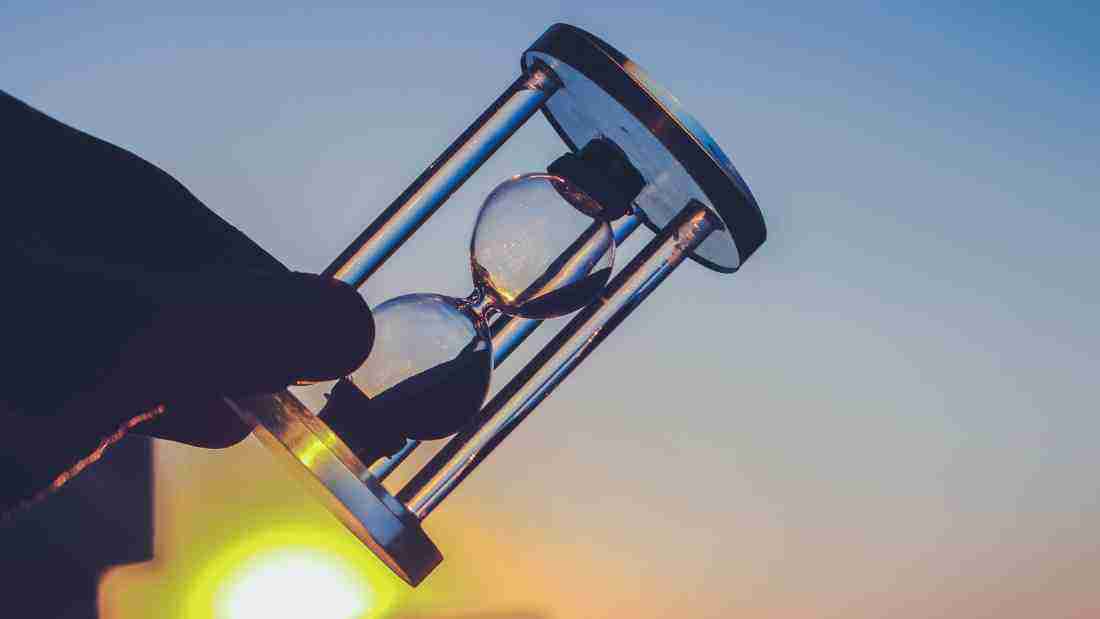A man holding an hour glass, denoting the passage of time
