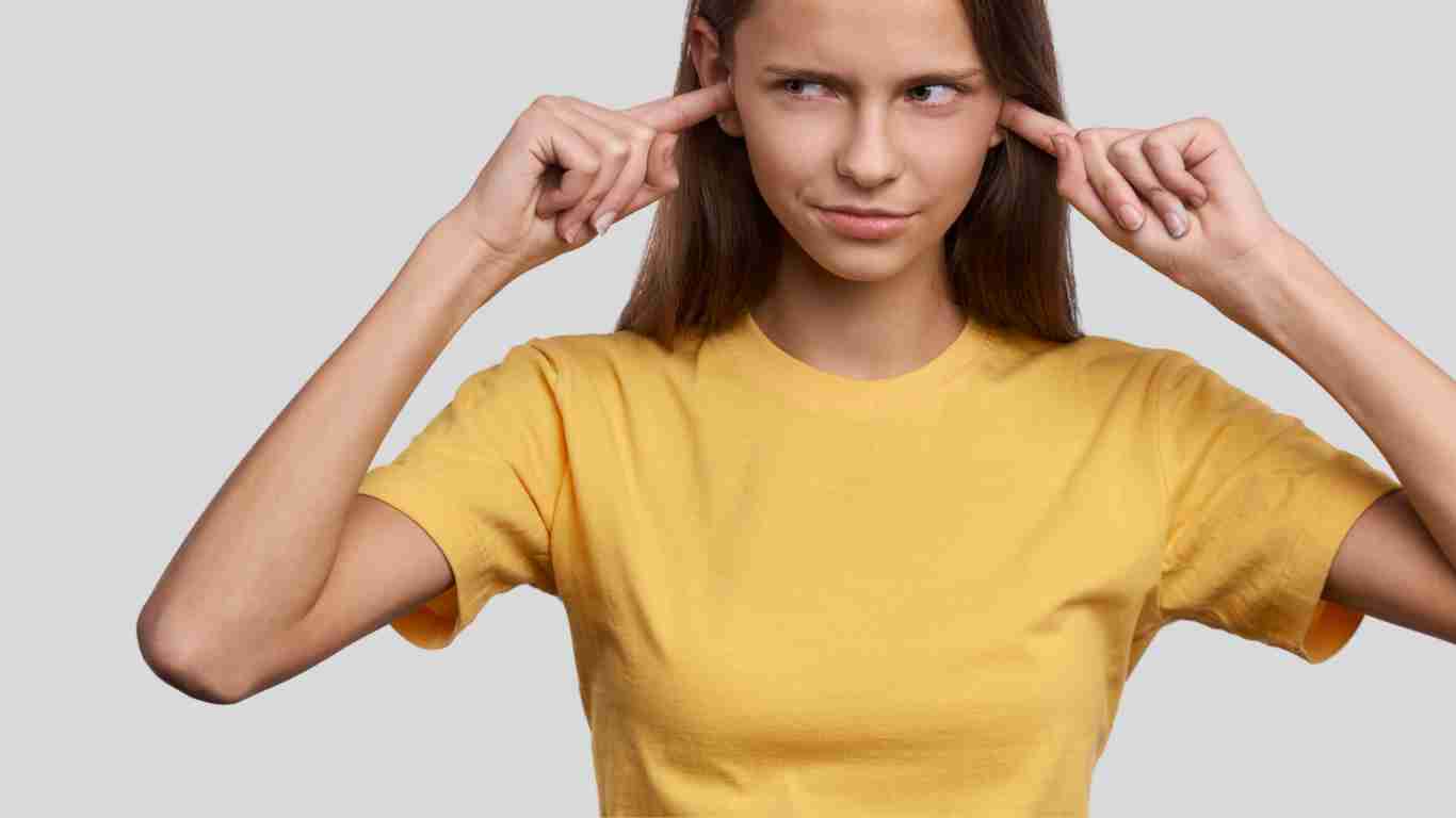 A woman with her fingers in her ears so she cannot hear