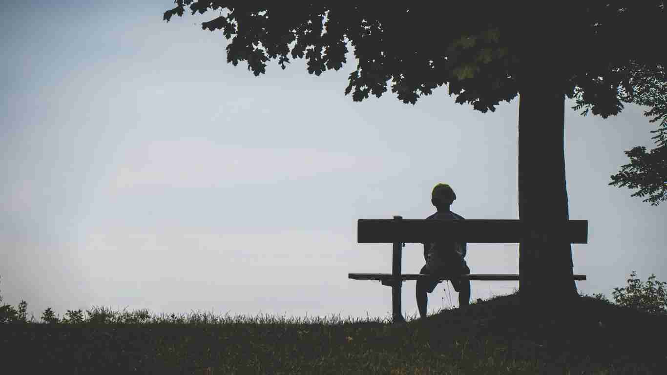 A man sitting alone on a bench in the dark