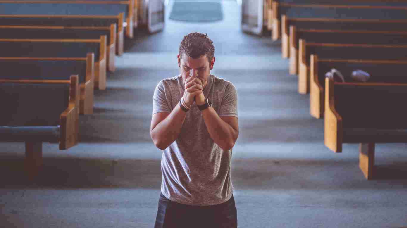 A man praying in the aisle of a church