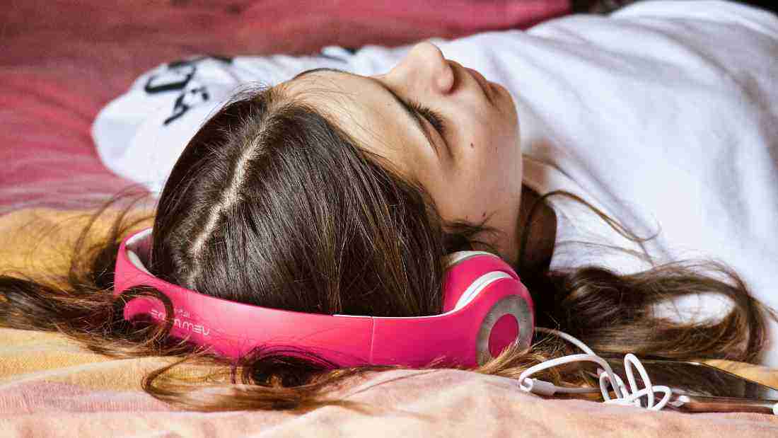 A young woman wearing pink headphones