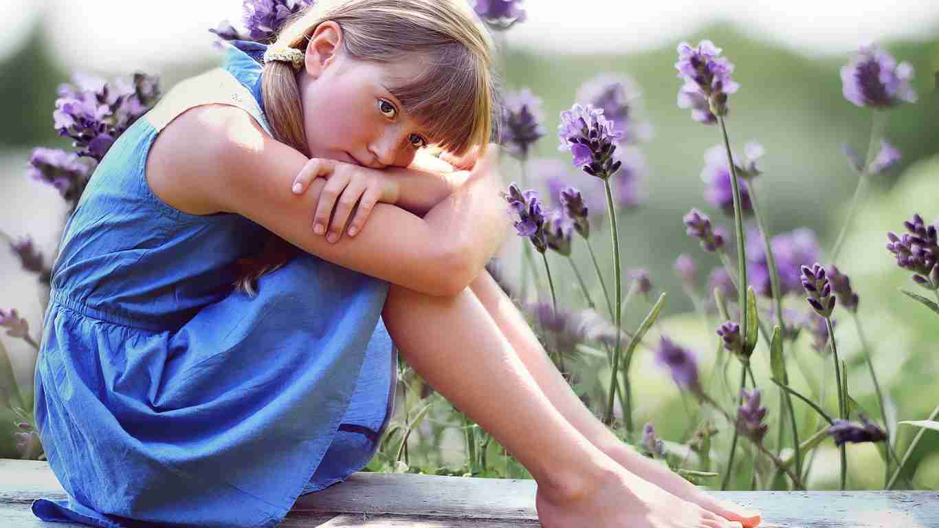 A little girl who appears to be sad, sitting alone in a garden