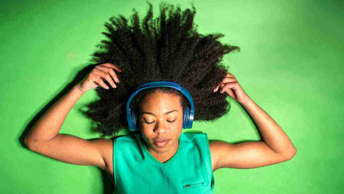 A young woman lying on a bed and listening to music