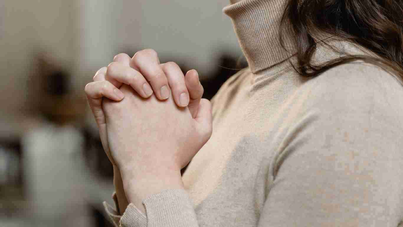 A woman with her hands clasped in prayer
