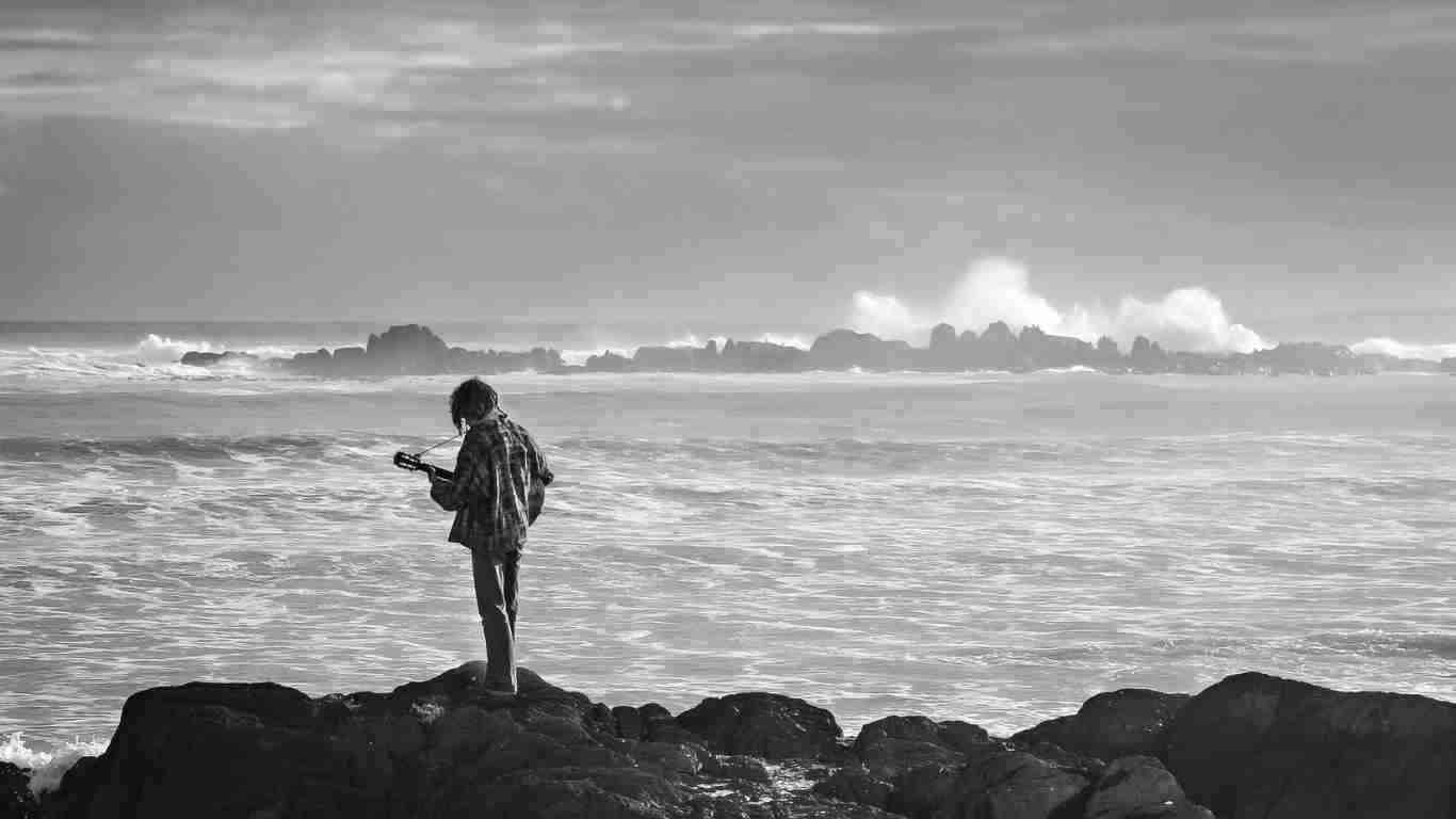 An isolated young man staring at the rough sea