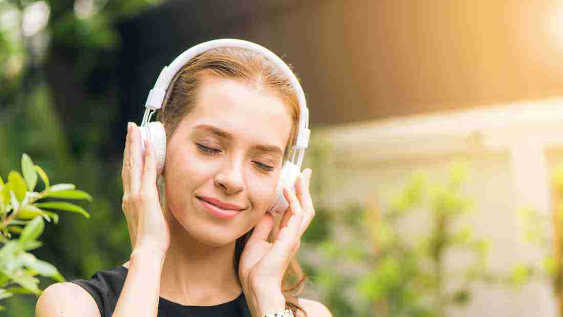 A woman listening to music in a garden