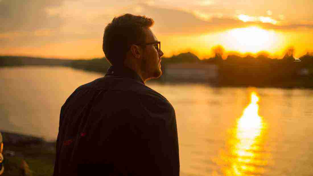 A depressed man watching the sun set