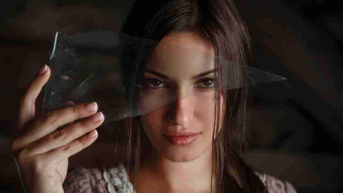 A woman holding a sharp shard of glass
