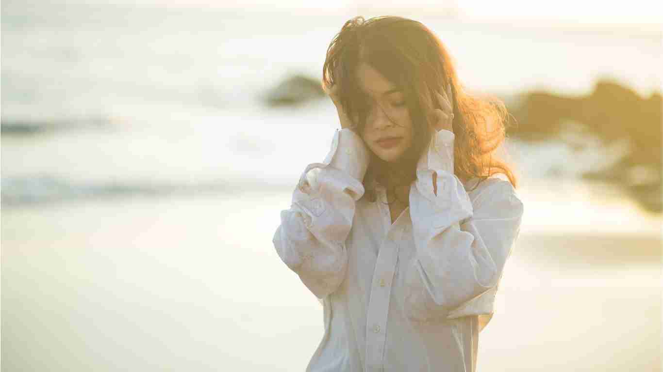 A sad woman crying as she walks along a beach