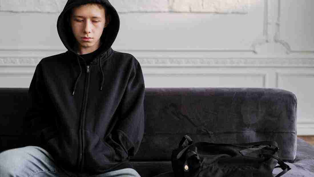 A sad young man sitting alone on a sofa