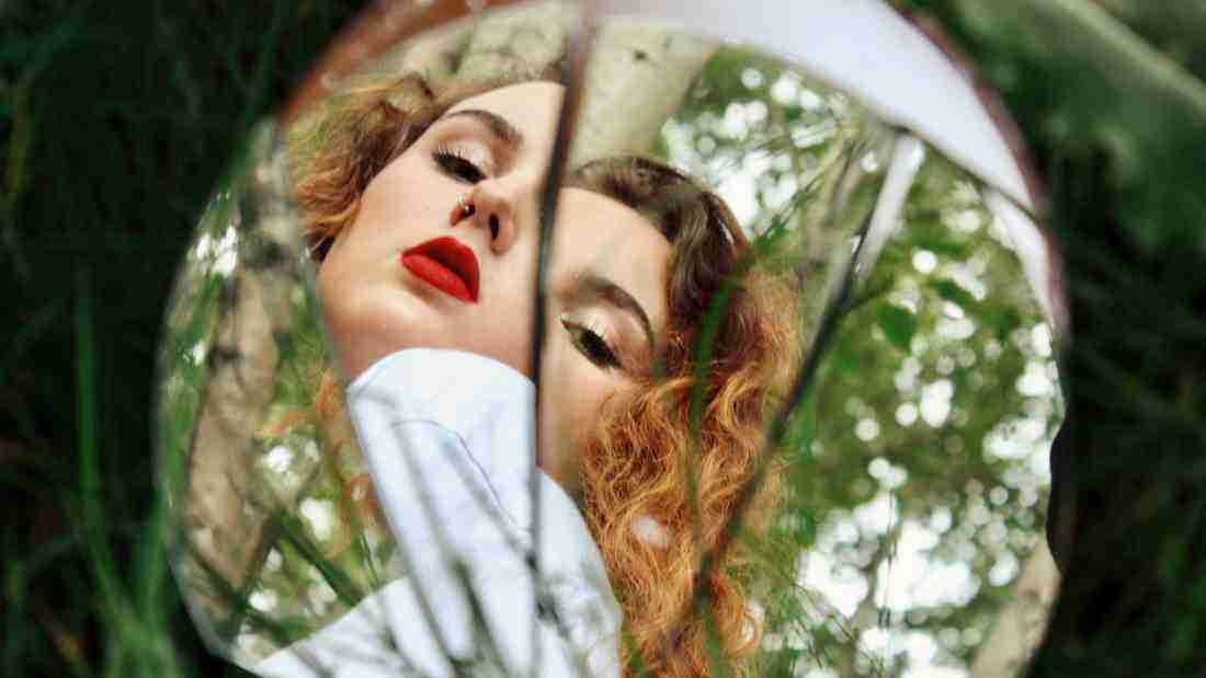 A woman gazing into a broken mirror