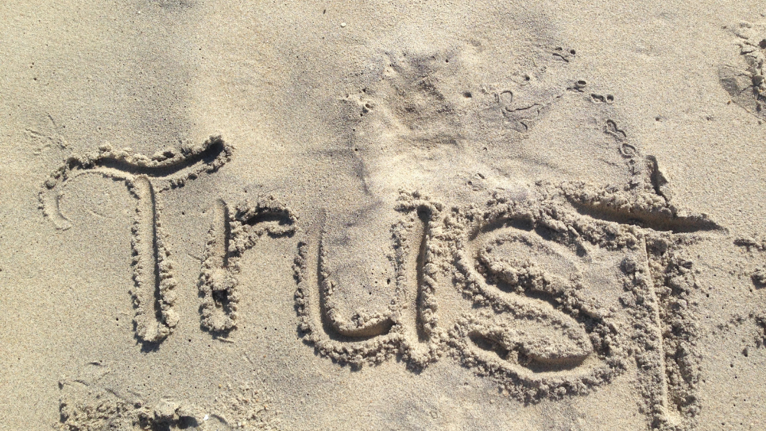 The word TRUST written in the sand