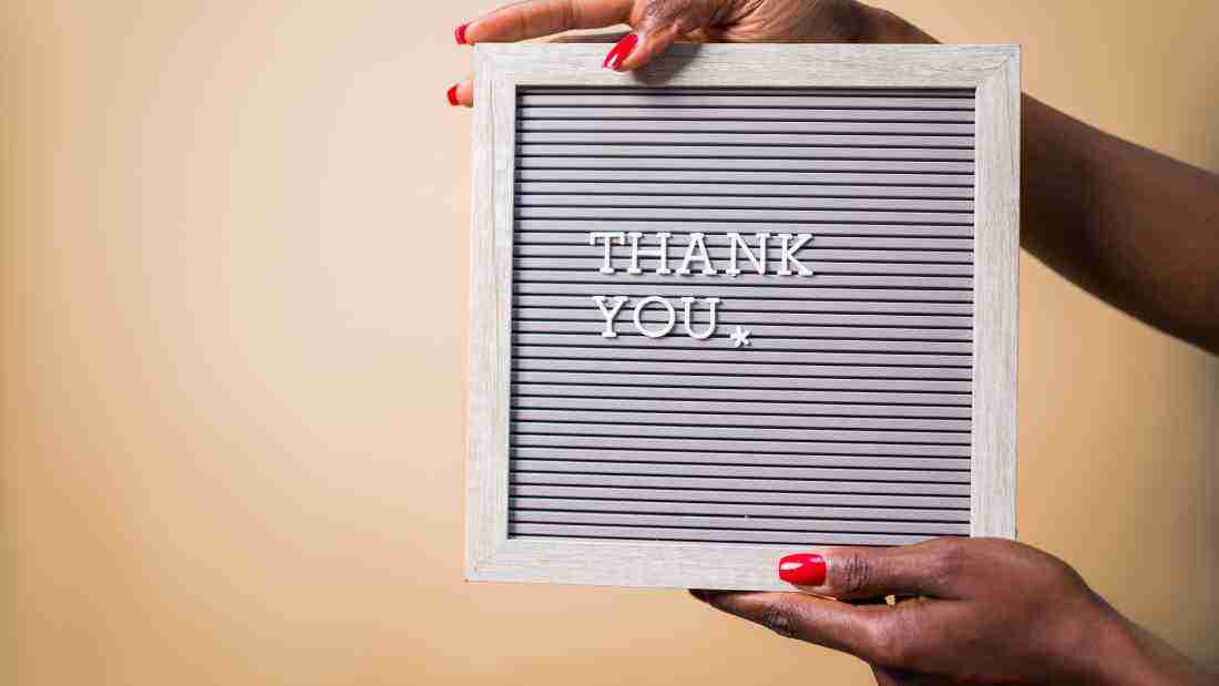 A woman holding up a sign with the words THANK YOU written on it