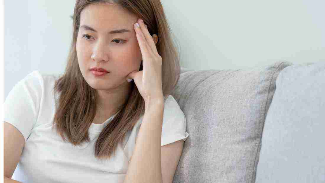 A distraught woman sitting alone on a sofa