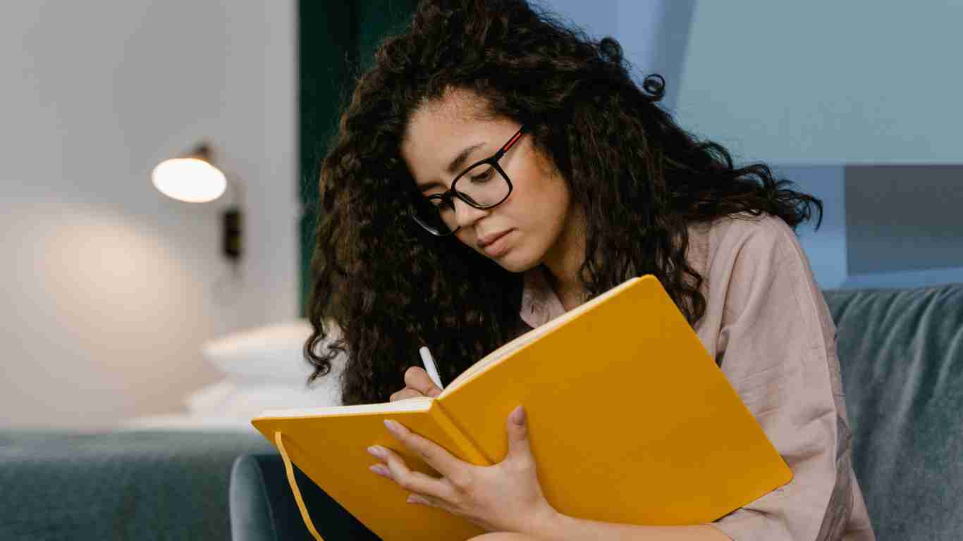 A woman sitting on a sofa and writing in her journal