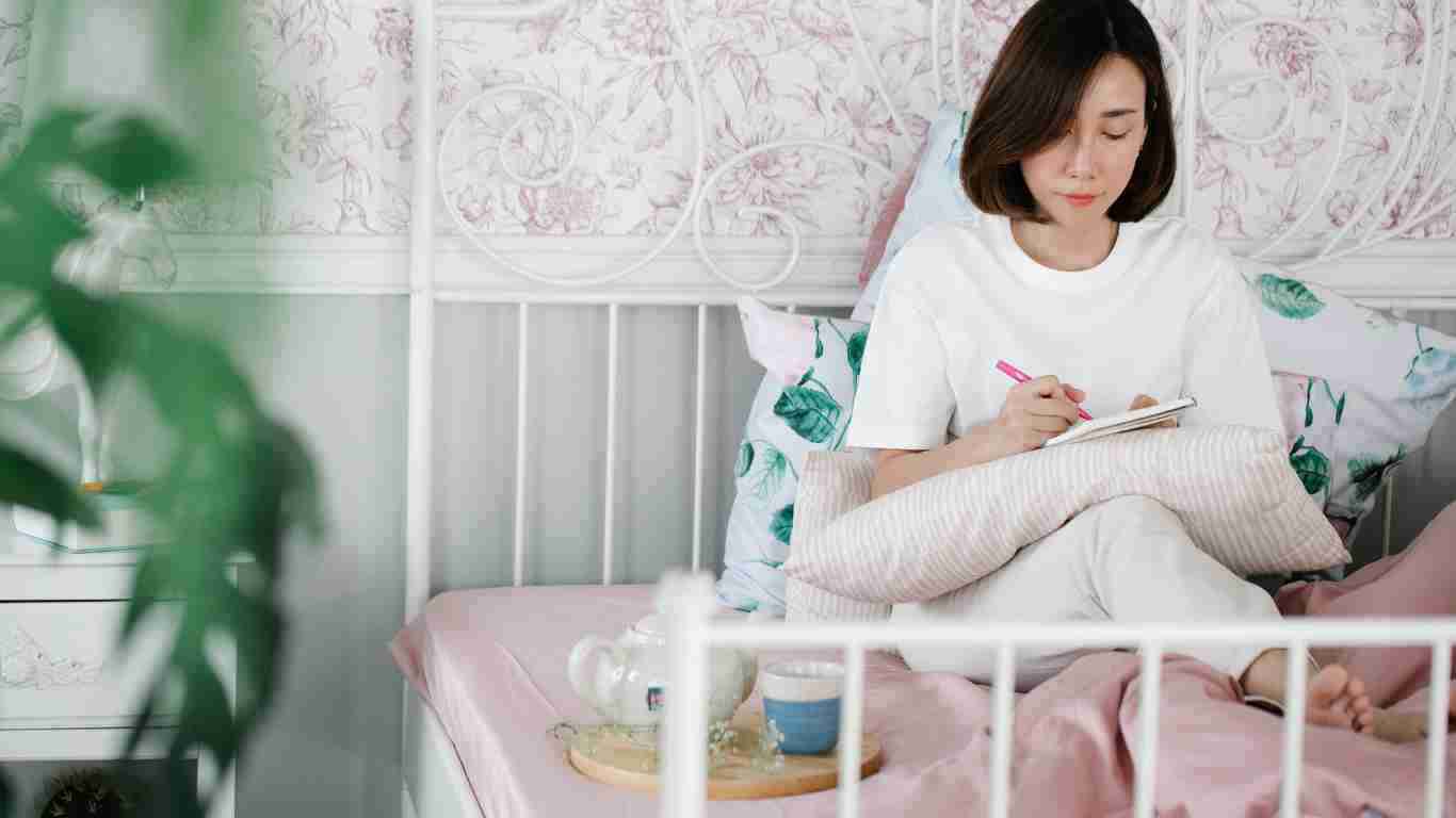 A woman writing in her journal while cuddled up in bed