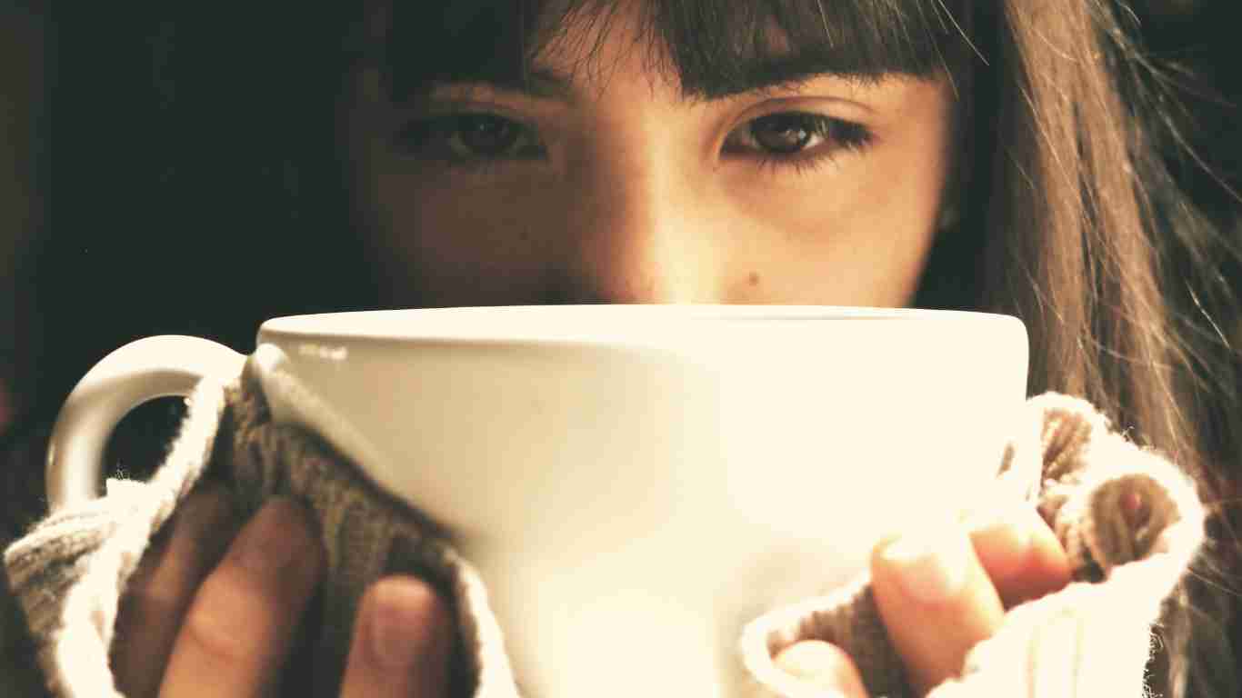 A woman drinking a big coffee of coffee and totally savouring the moment