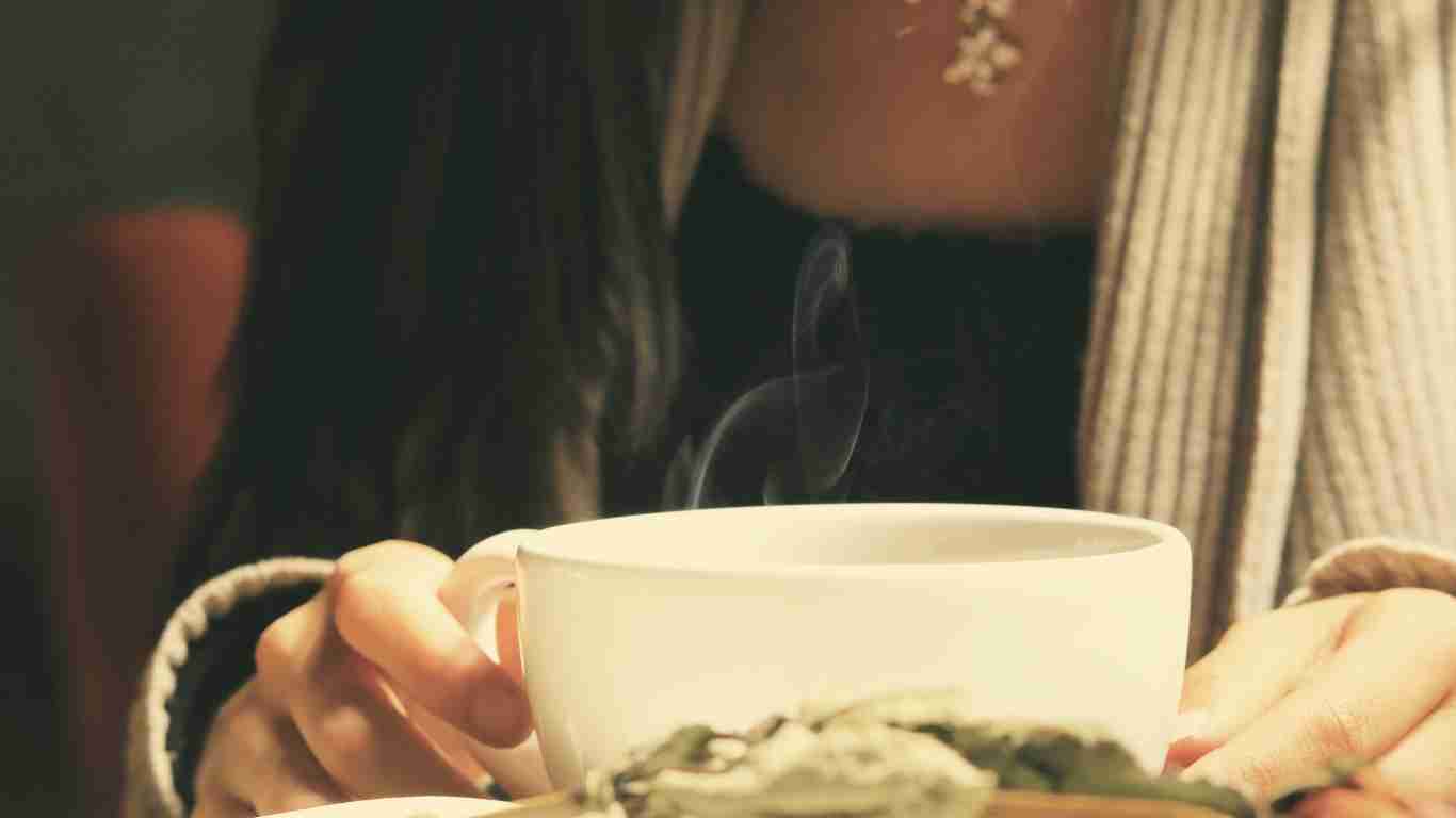 A woman reading a book and savouring a cup of coffee