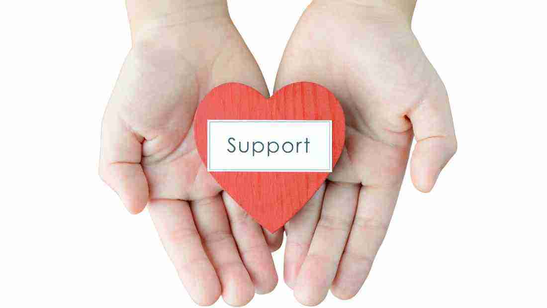 Hands holding a heart with the word support written on it