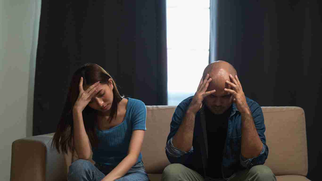 An unhappy couple sitting on a sofa